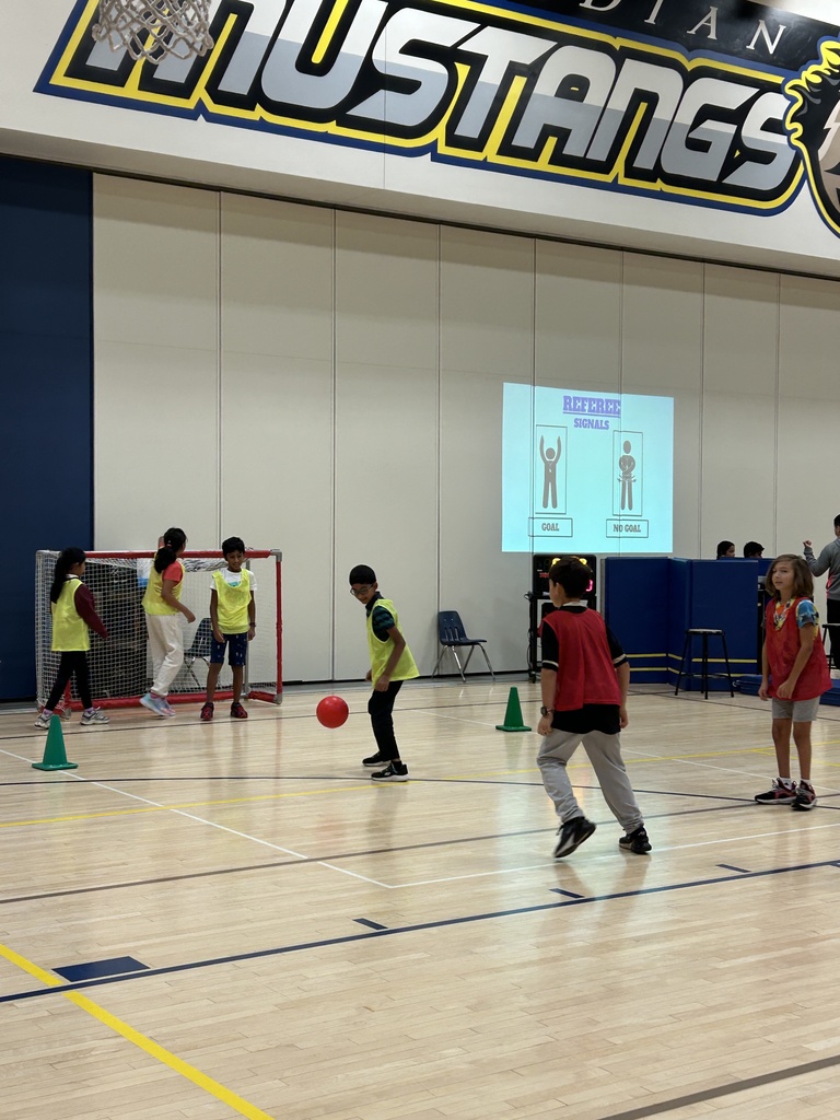 Students playing soccer in the gym.