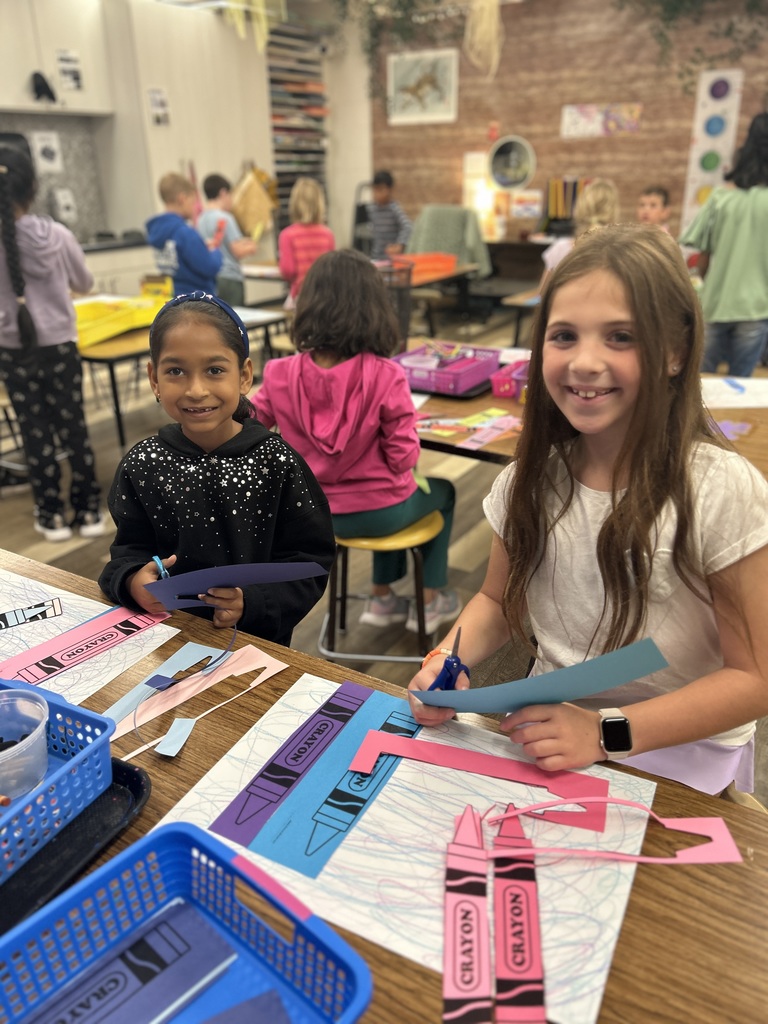 STudents sitting at a table and working on a crayon craft.