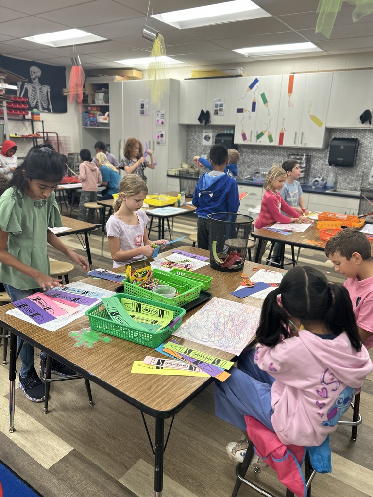 STudents sitting at a table and working on a crayon craft.