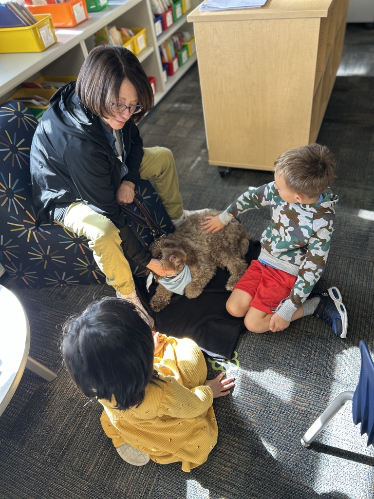 Students sitting on the floor with a dog.