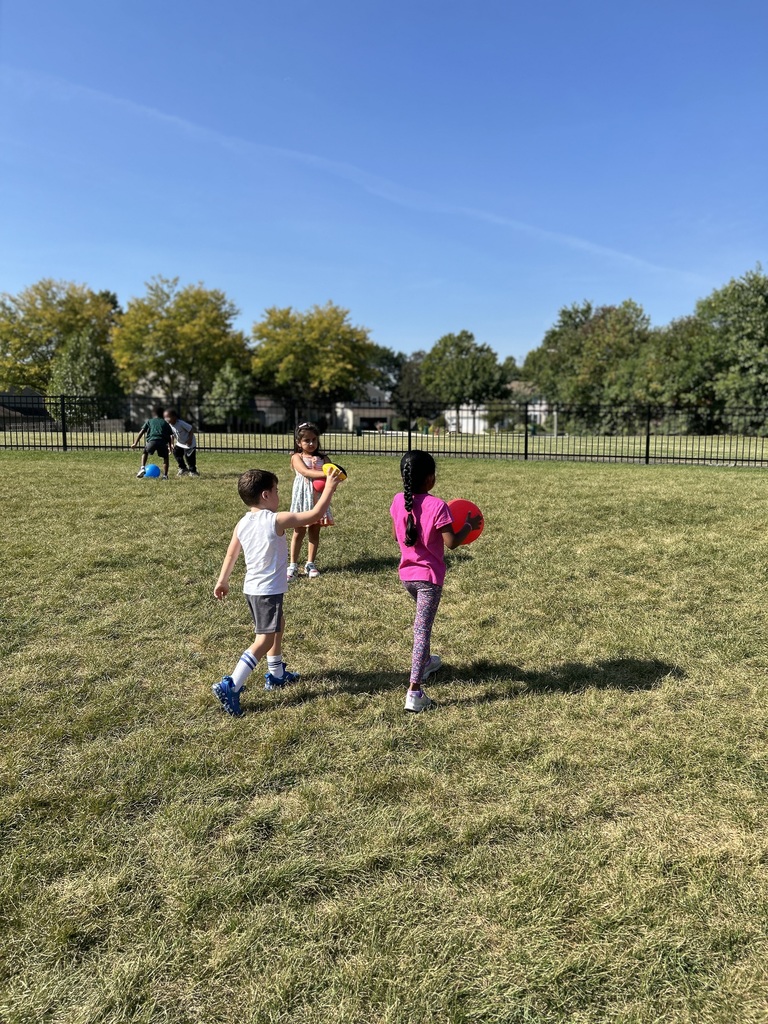 Students holding a ball in the grass.