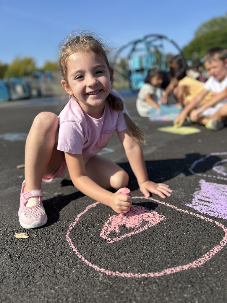 Student coloring with chalk outside.