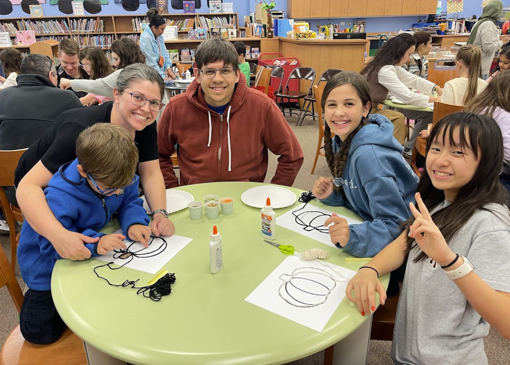 Families sitting together making a craft.
