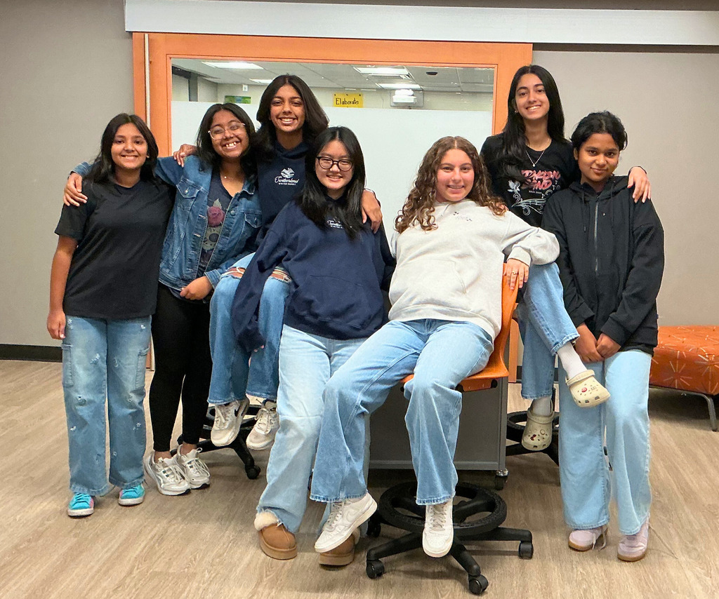 Girl students wearing jeans and smiling.