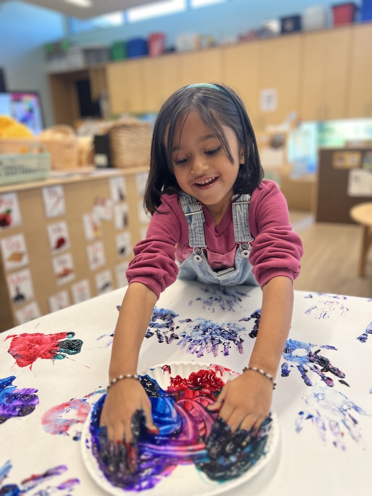 Student finger painting at a table.