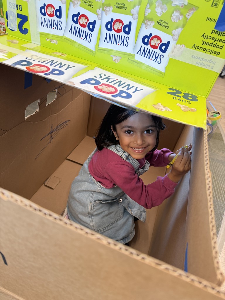 Student smiling and sitting in a box.