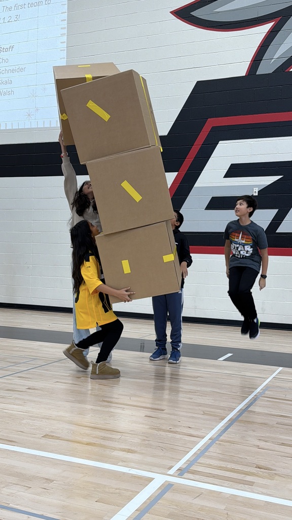 Students stacking boxes on top of one another in the gym.