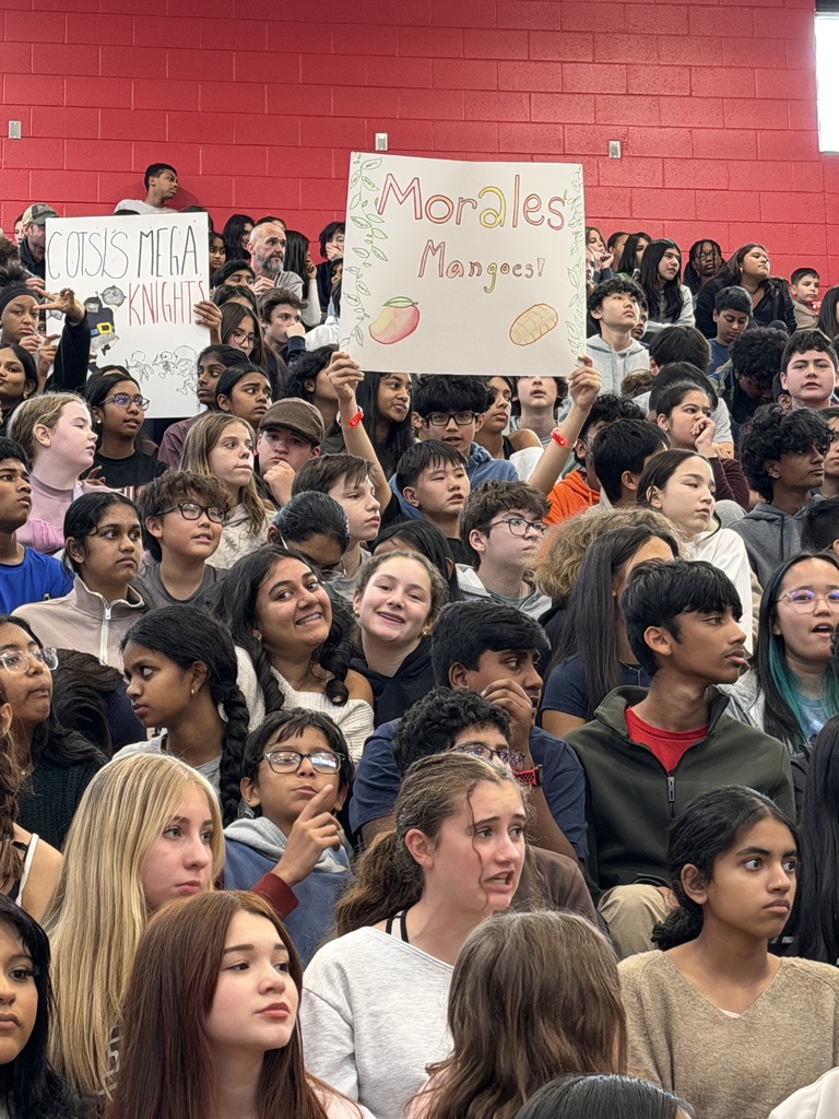 Students holding up signs in the bleachers.