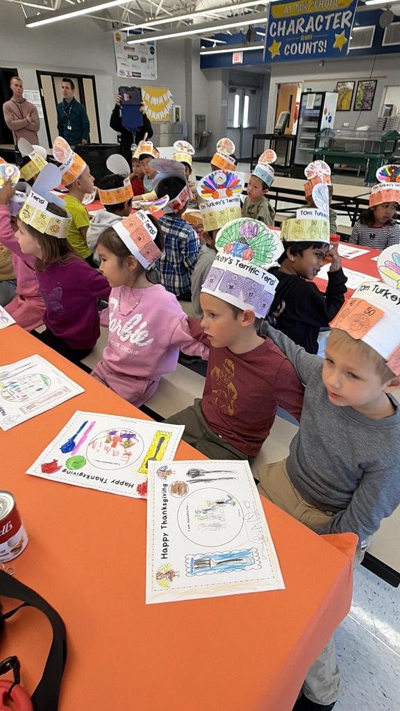 Students sitting with arms around each other at a table singing a song.