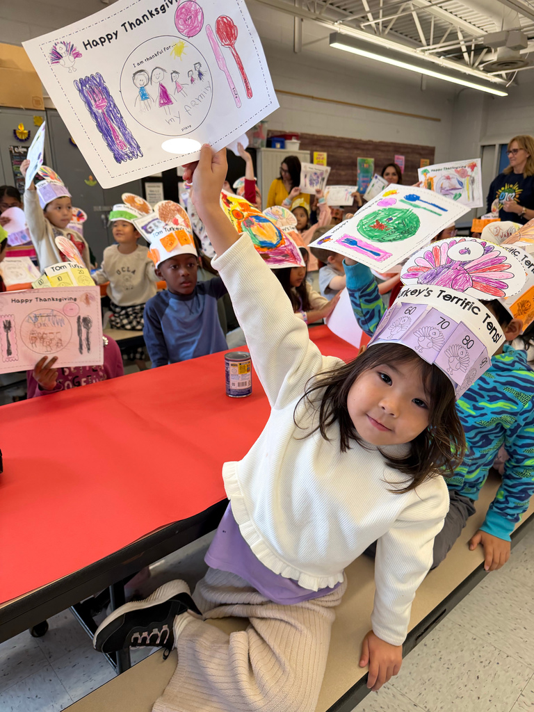 Student holding up her menu with a hat on.