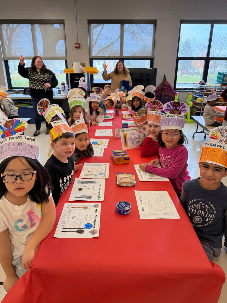 STudents smiling at a table with their hats and menus.
