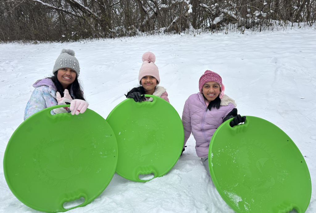 Girls holding their sleds.