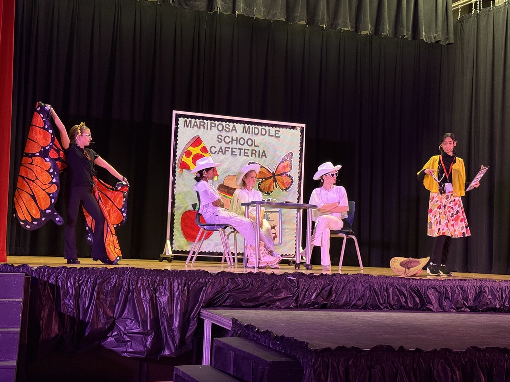Students on stage in costume performing a play.