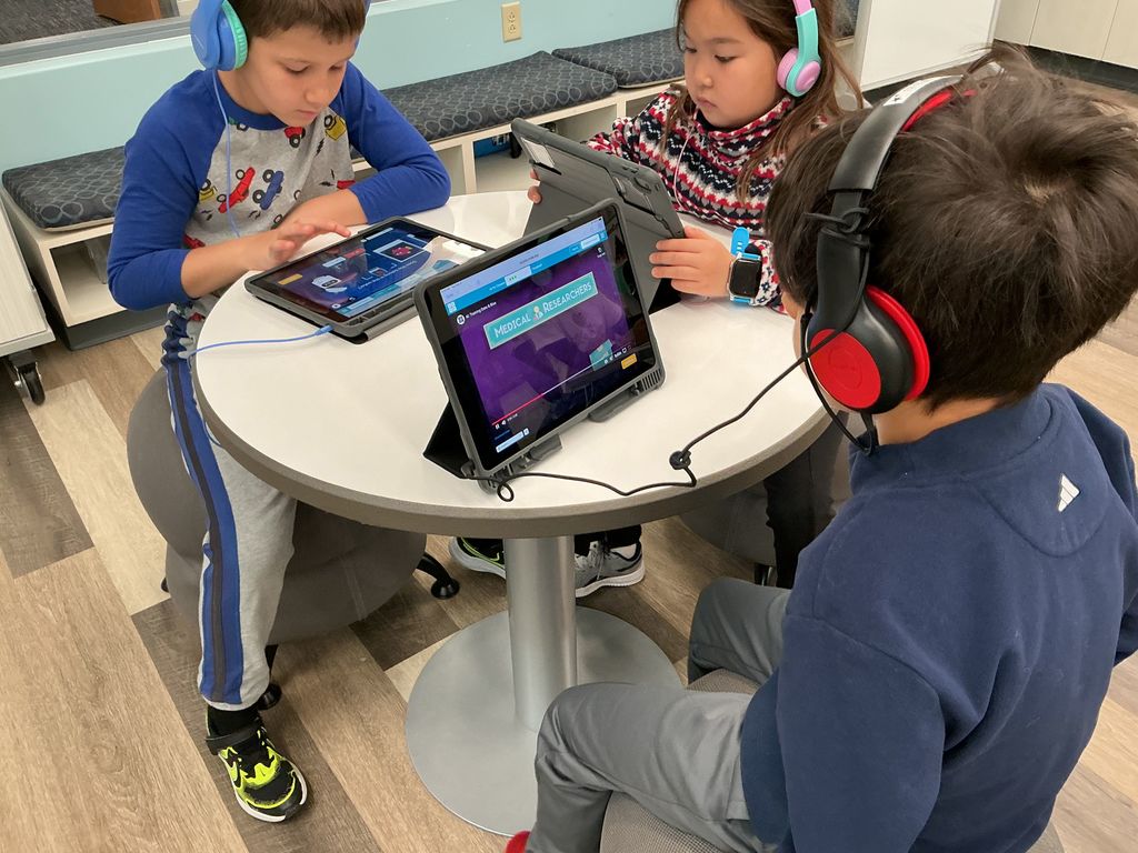 Students sitting at a table working on iPads