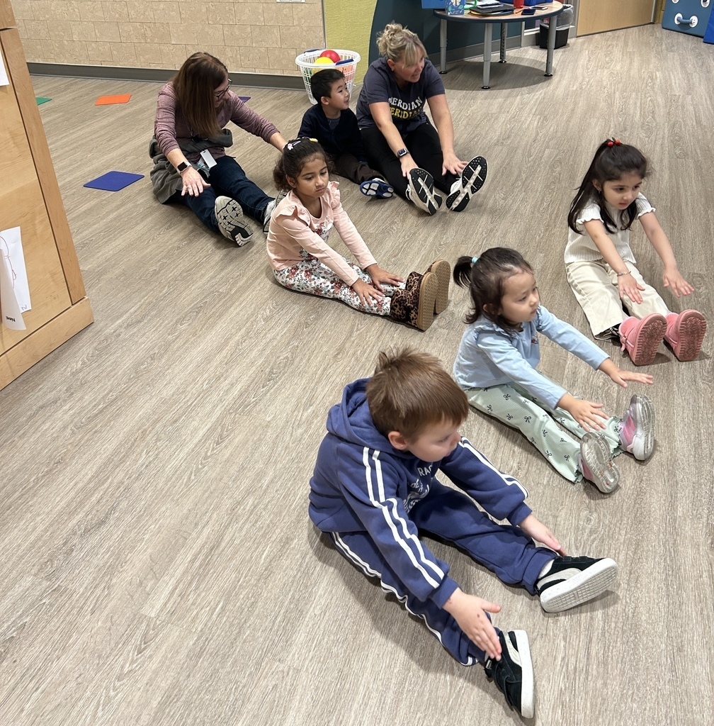 Students stretching on the floor with two teachers.