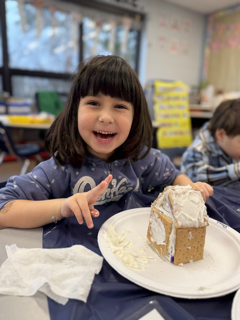 Student smiling while decorating her gingerbread houses.