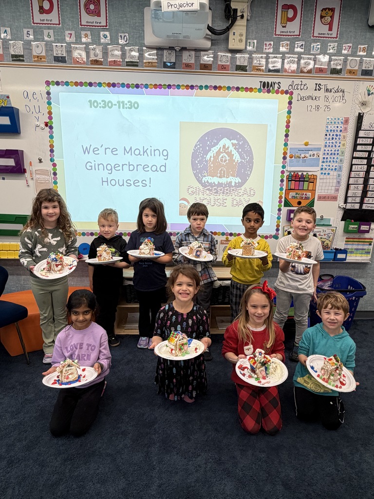 Students standing with their gingerbread houses.