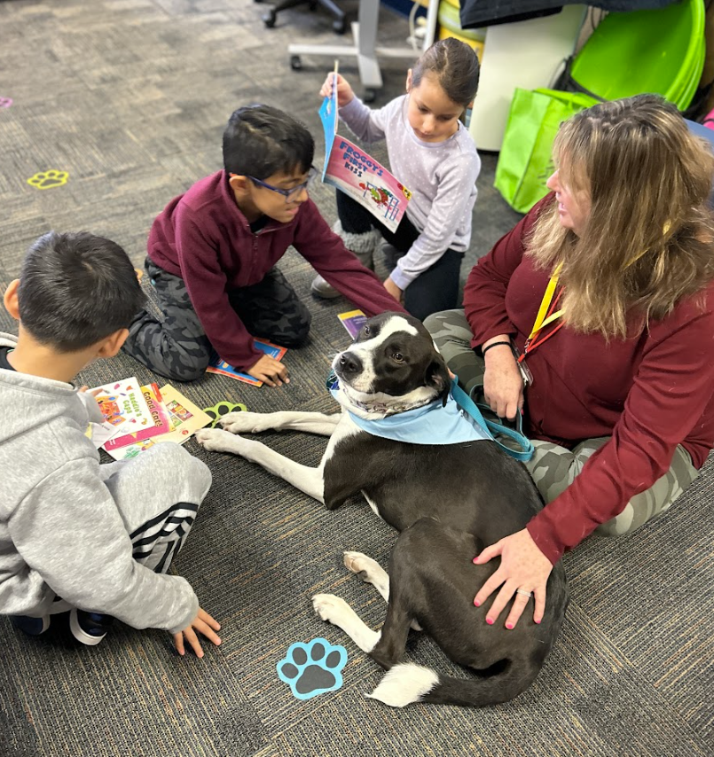 Students reading a book with the dog.