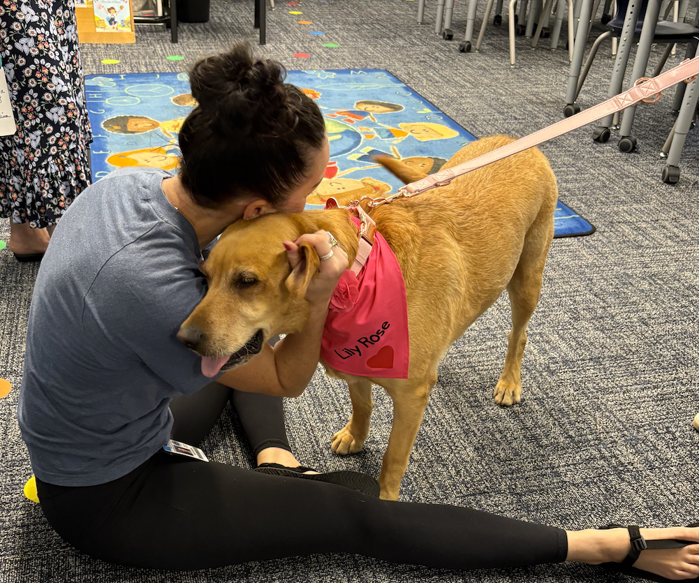 Teacher hugging a dog.