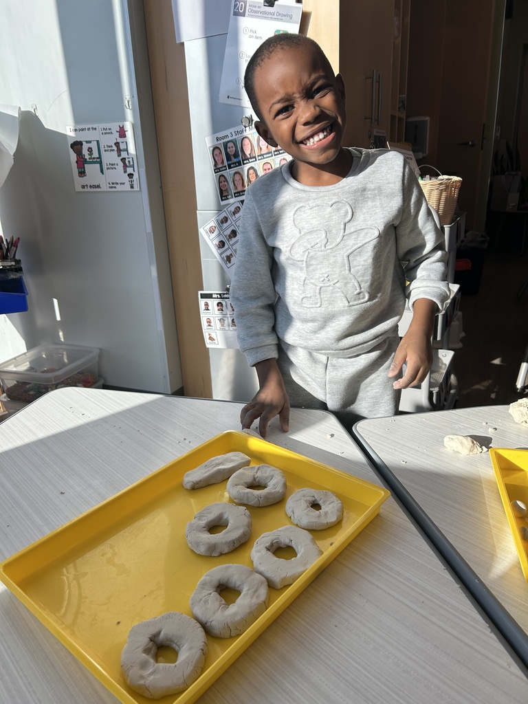 Student smiling with a tray of pretend donuts made out of playdoh.