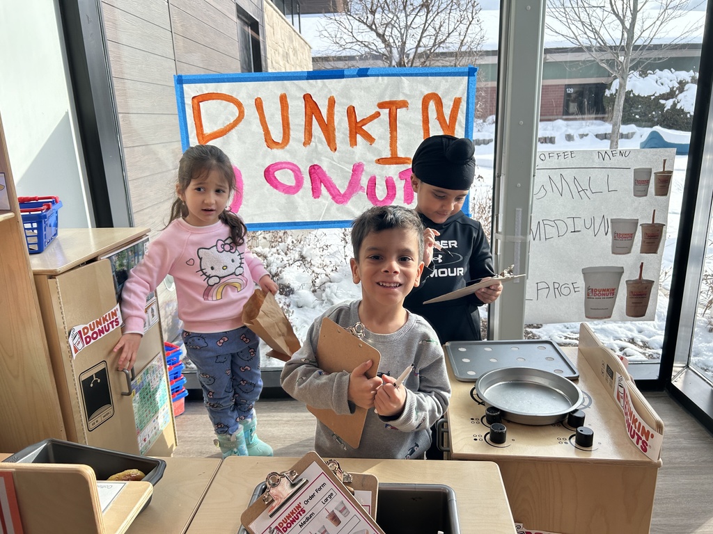 Students smiling by their pretend Dunkin store.