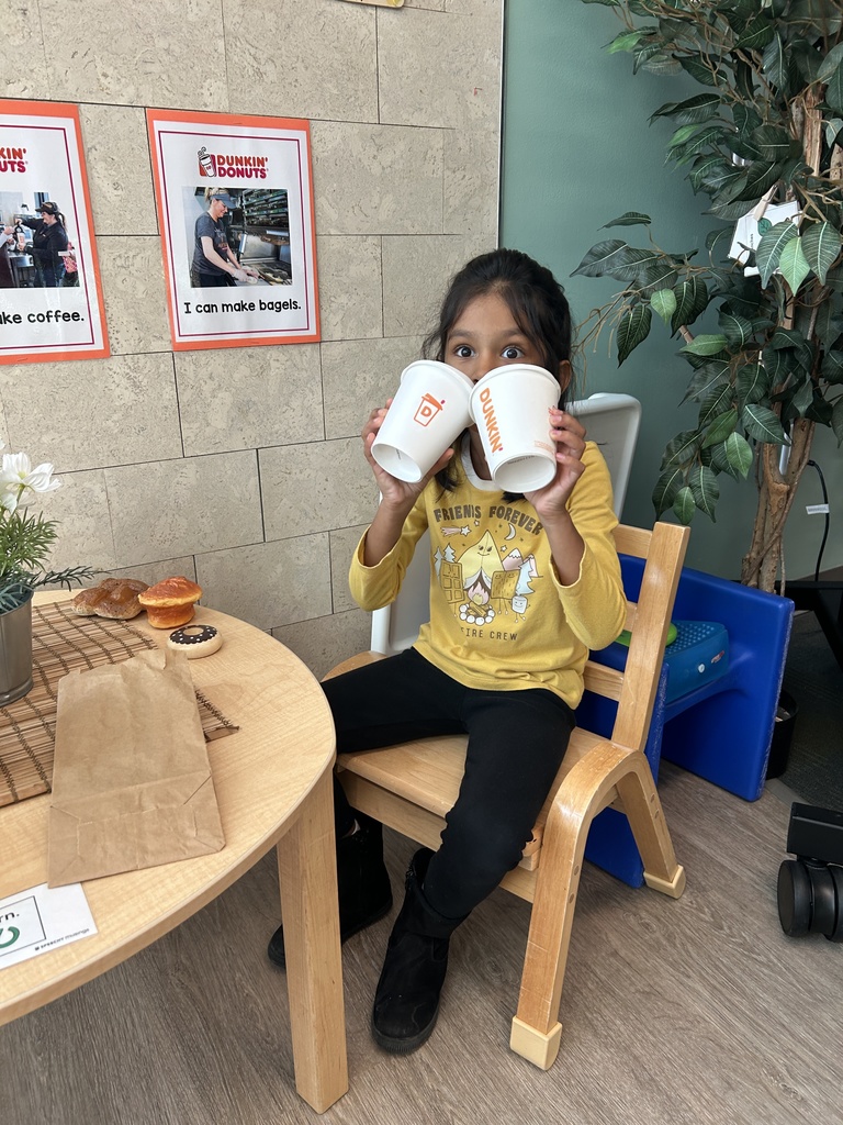 STudent holding up two cups like she is drinking from them.