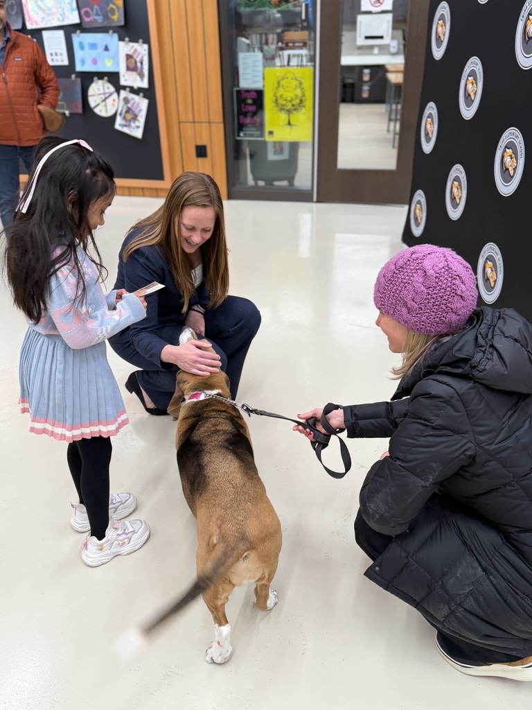 Dr. McIntyre stands with a student and a therapy dog.
