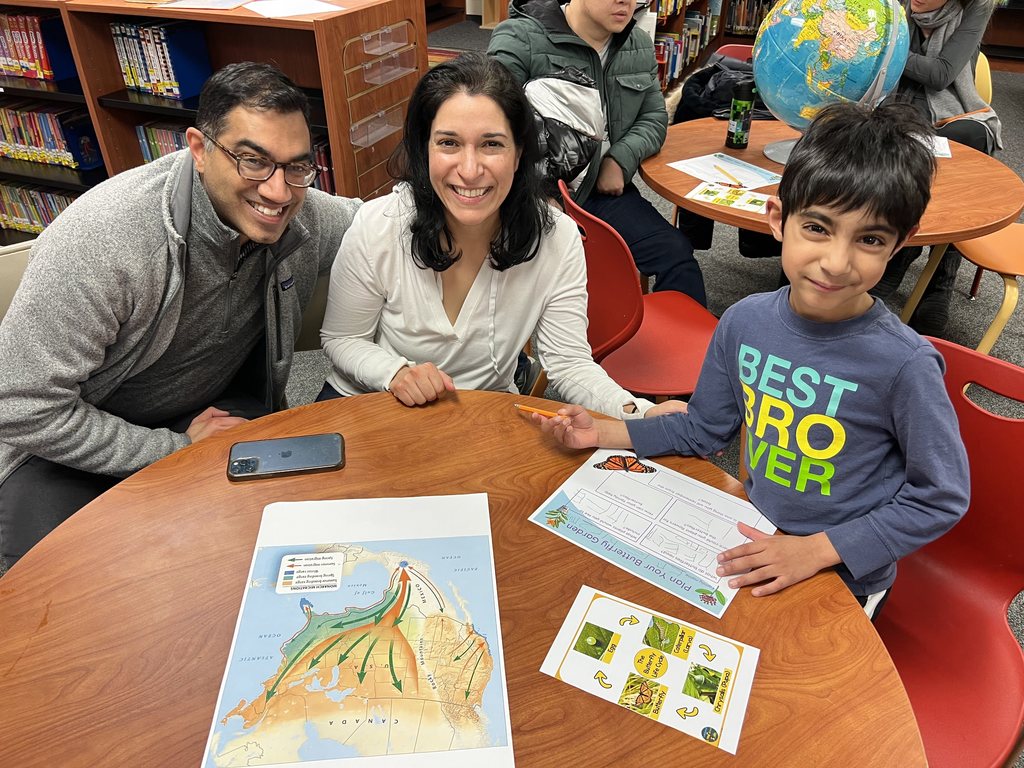 Student with their mom and dad sitting at a table.