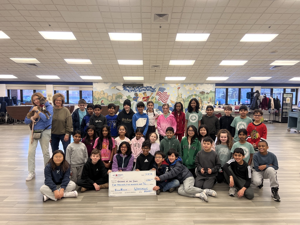 Students standing with a dog, teachers and a giant check.