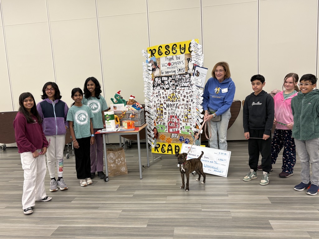 Students standing with a dog, a former teacher, and donations.