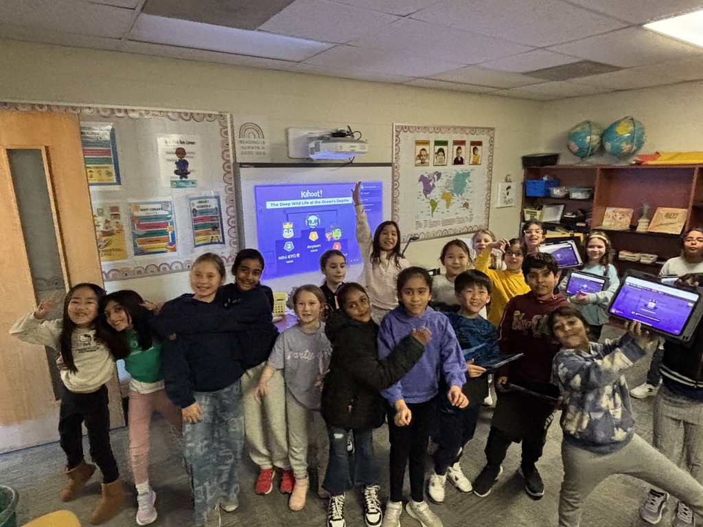 Students standing together in a group smilling and holding up iPads.
