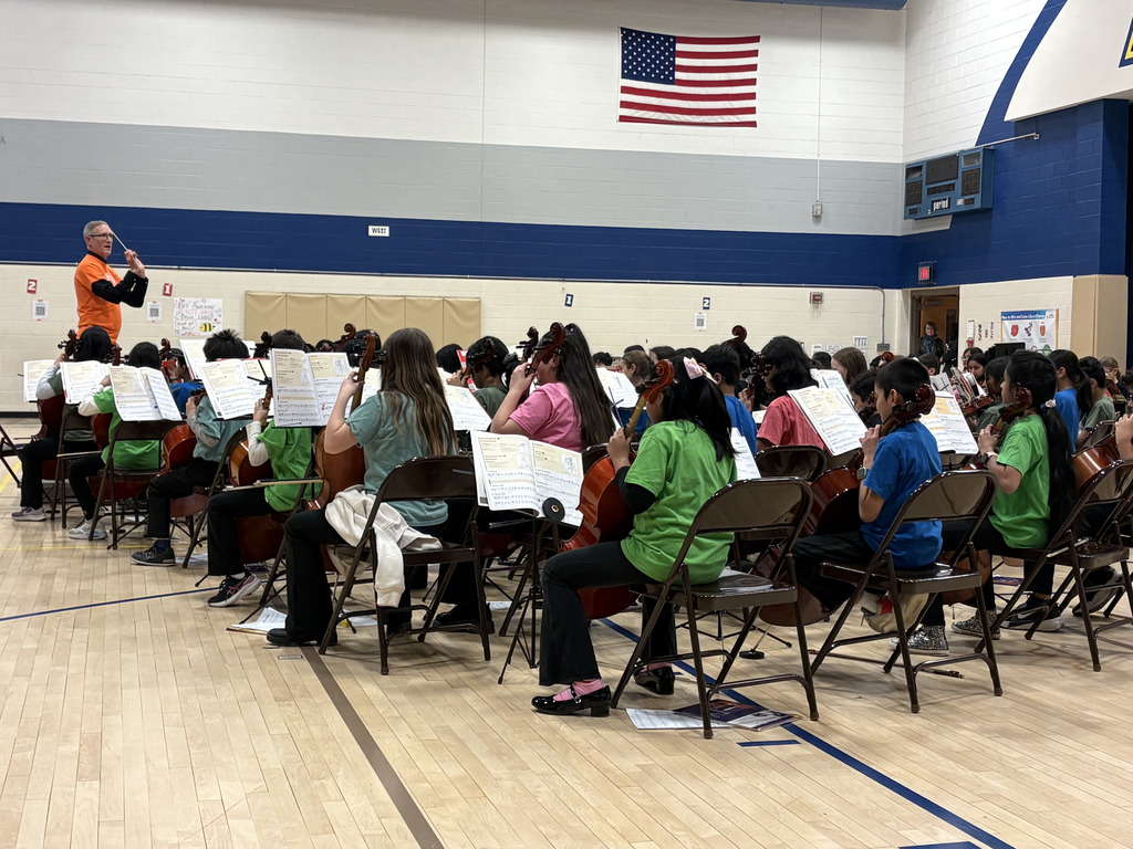 A group of students sitting in the gym with instruments under the direction of Mr. Jenkin.