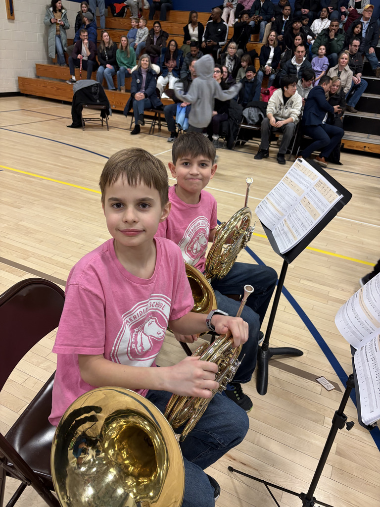 Two boys wearing pink Meridian shirts holding their instruments. 
