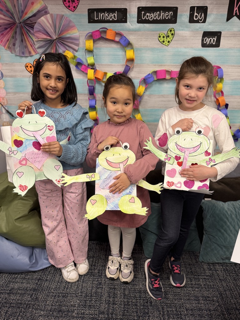 Three girls holding up their frog bags.