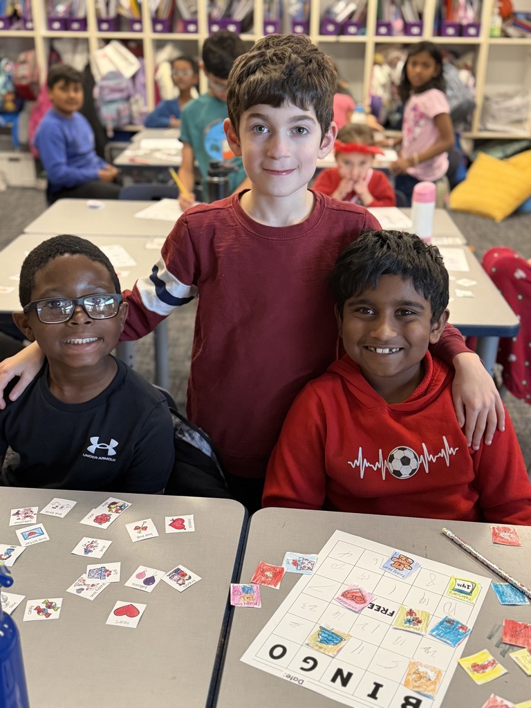 3 boys sitting together with Valentine Bingo at their desks.