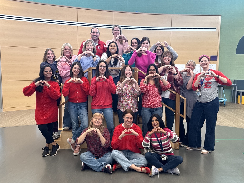 Group Photo of teachers wearing valentines colors and making heart hands.