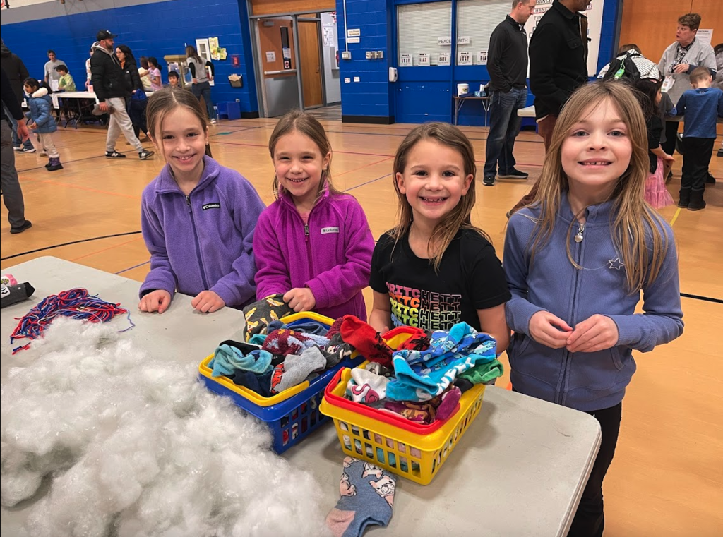 Students working with stuffing and socks at a table.