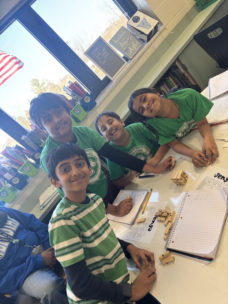 Students sitting at a table with Jenga pieces. 