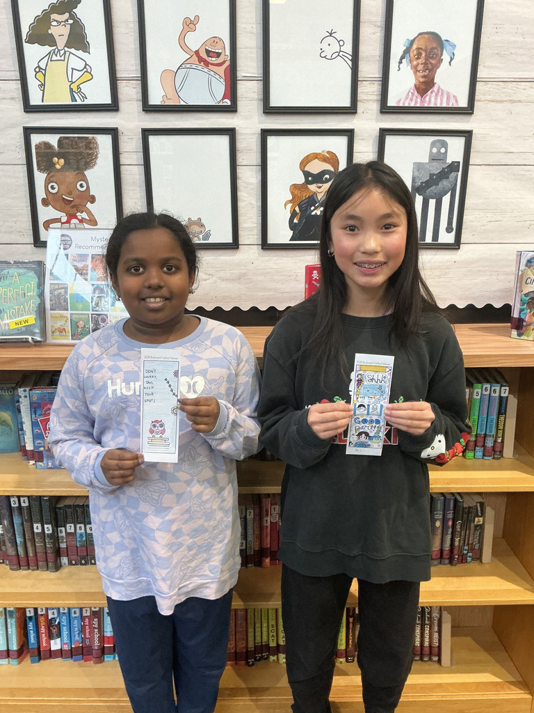 Two students holding up a bookmark.