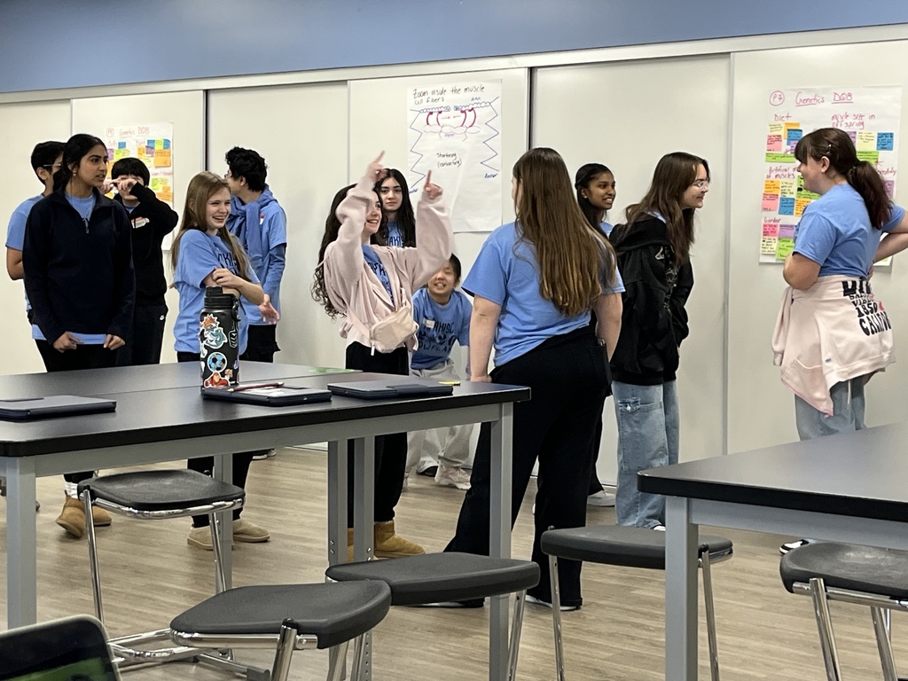 A candid photo of a group of students standing, smiling and laughing. 