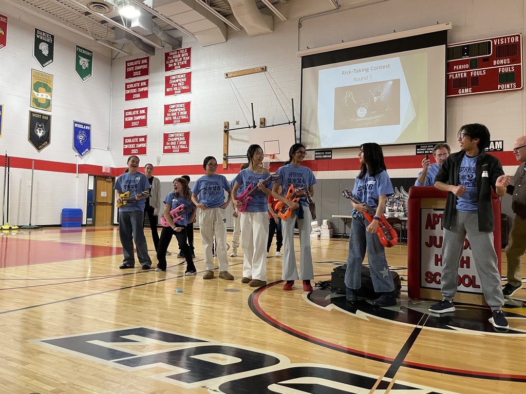 Several students standing in front of the crowd with blow up guitars. 