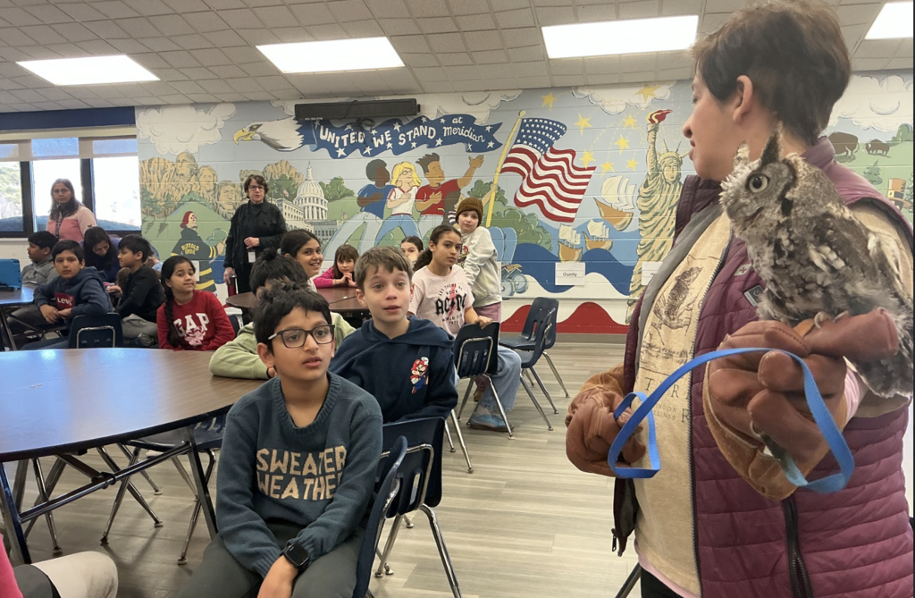 Owl handler standing with students. 