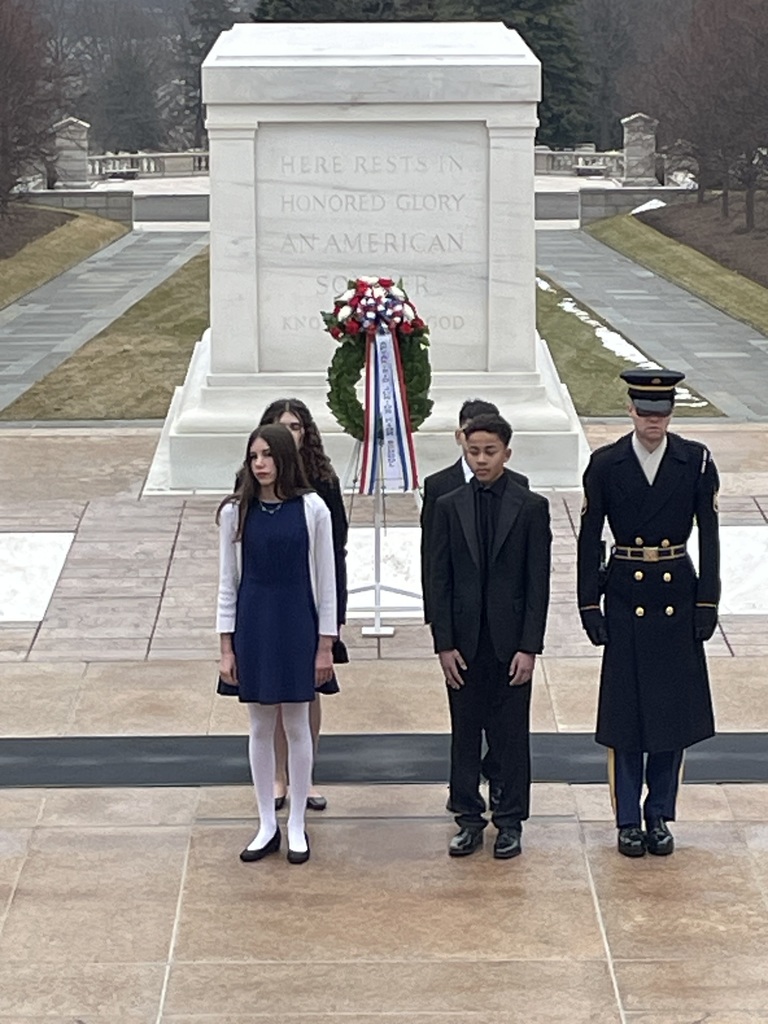Students standing with a guard for a ceremony.