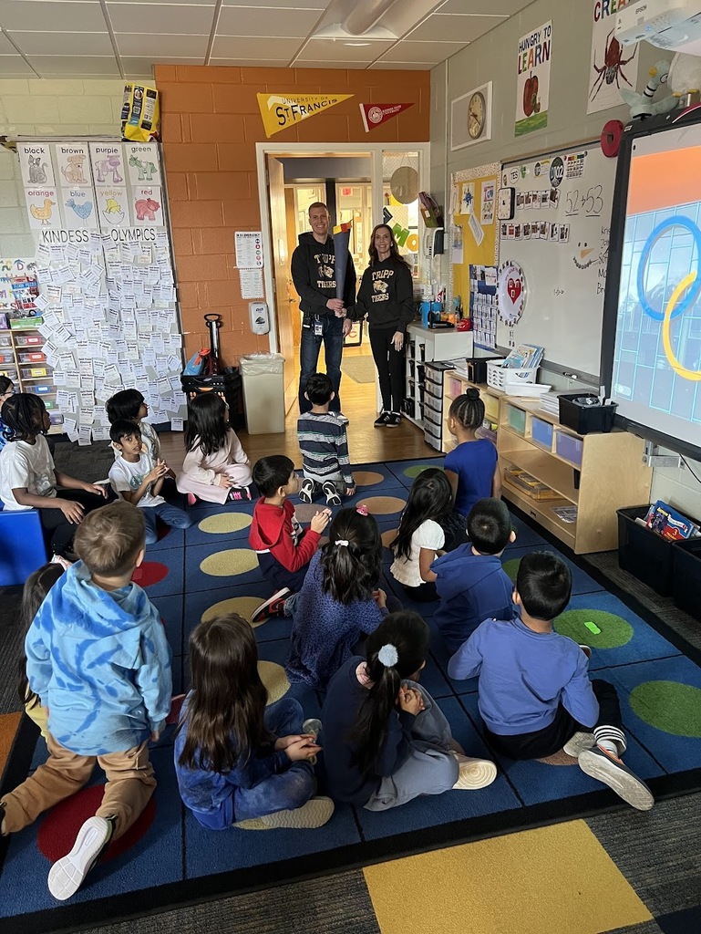 Two principals standing in the door holding a torch with the class sitting on the floor watching.