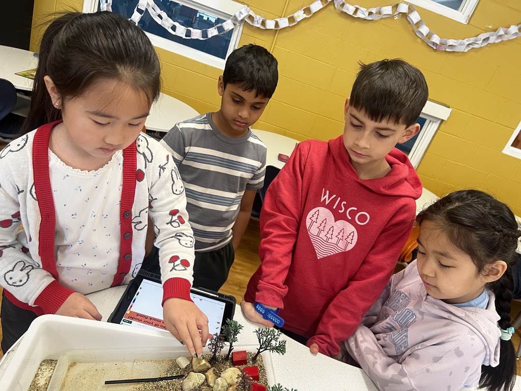 Students working standing around a table.