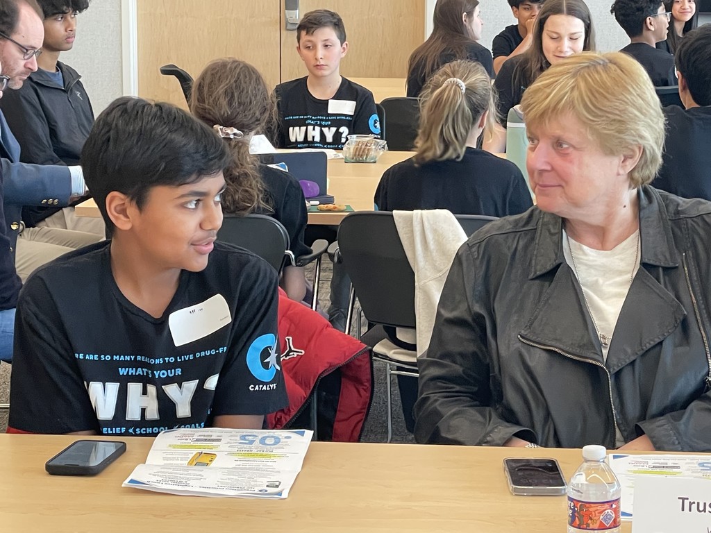 Student talking to a trustee at a desk.