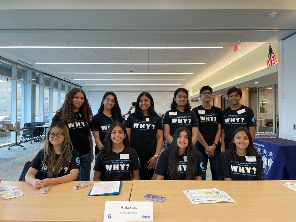 Students sitting at a desk, wearing their "whats your why?" shirts.