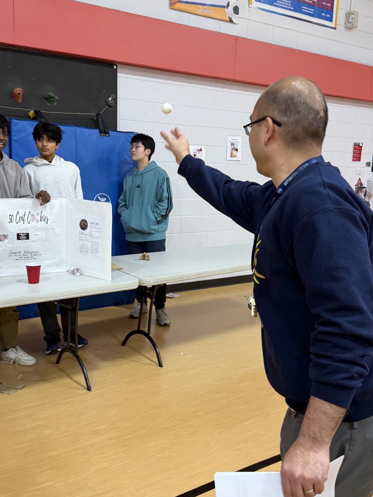 Mr. Cho shoots a ball into a cup at a business fair in the gym.