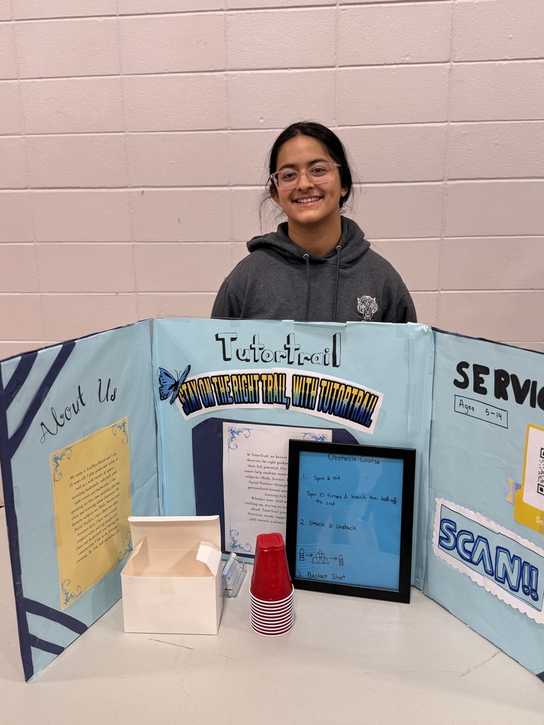 Student standing at a table at a business fair.