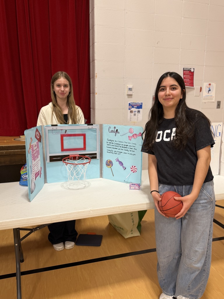 Two girls standing at a table with a basketball hoop and project.